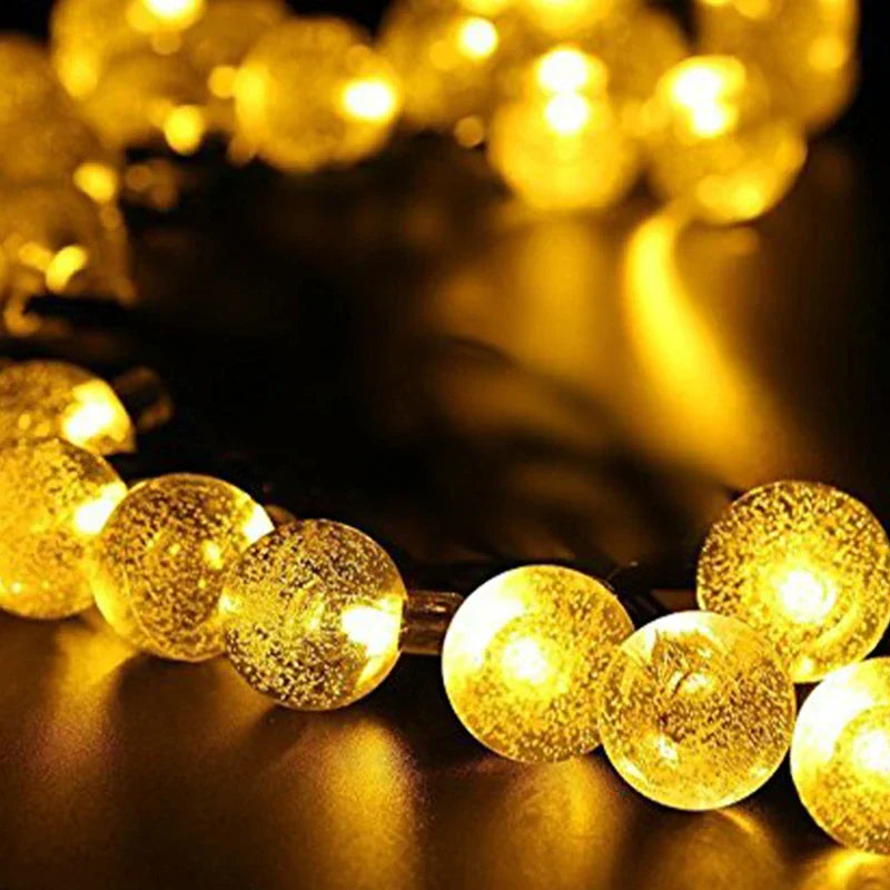 Bubble Ball Lights - Warm lit textured round bulbs laid out on a smooth dark reflective surface