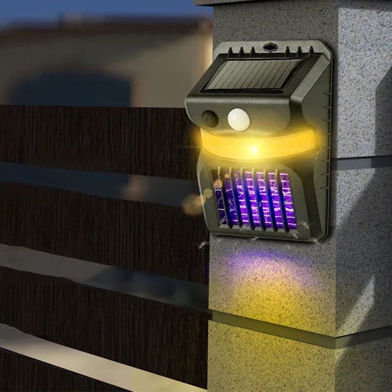matamoscas solar para mosquitos - Unidad montada en pared instalada en un poste de piedra exterior, con luz LED iluminada y rejilla eléctrica púrpura activa que atrae insectos voladores