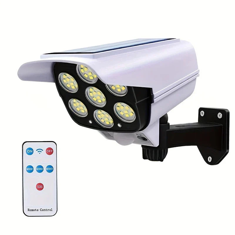 Solar powered dummy camera with 7 LED lights, black mounting bracket, and small remote control against white background