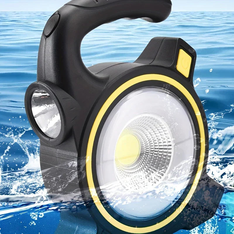 Black and yellow camping lantern with side flashlight, surrounded by splashing blue water