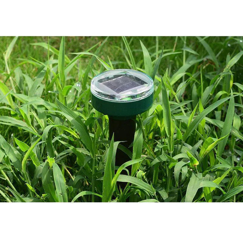 Solar Ultrasonic Mole Snake Repellent Spike - A solar pest repeller inserted into green grass, with its top solar panel visible above the blades