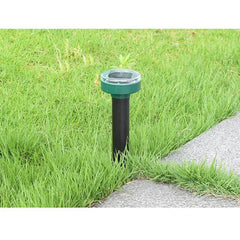 Solar-Ultraschall-Maulwurf- und Schlangenabwehr-Spike – Solarbetriebener Gartenpfahl, der in grünem Gras neben einer Betonpflasterplatte steckt
