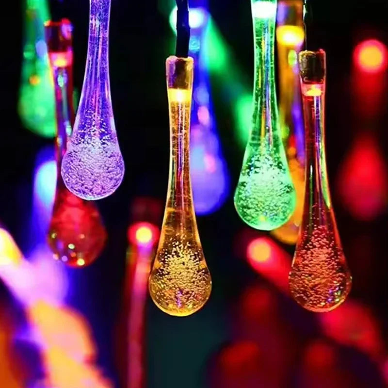 Nahaufnahme-Detail von mehrfarbigen Solarlichtern in Wassertropfenform für den Außenbereich mit durchscheinenden, blasentexturierten Tropfenlichtabdeckungen