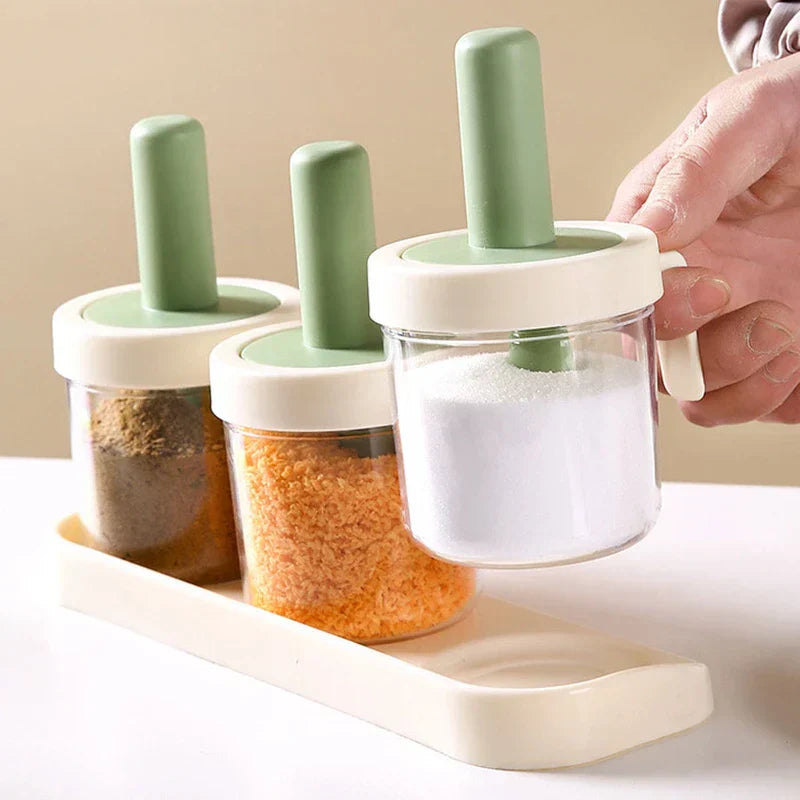 Spice Jar - Hand lifting one canister filled with white granulated salt from the storage tray, with two remaining canisters holding spices in place on the base