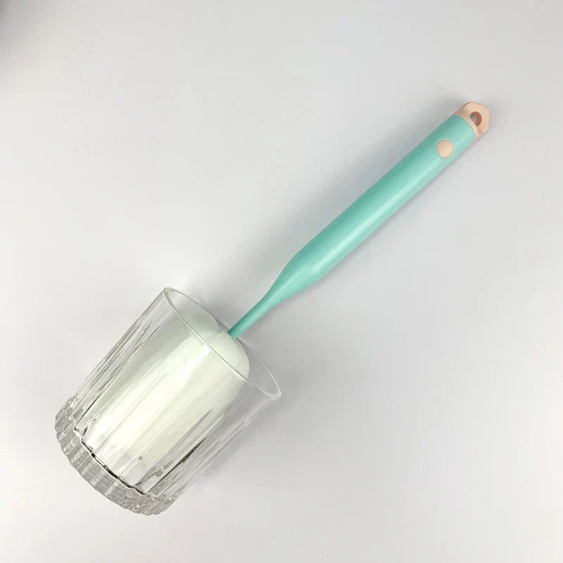 Sponge Bottle Cleaning Brush - A mint green handled sponge brush inserted into a clear glass, placed on a plain white surface
