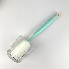 Sponge Bottle Cleaning Brush - A mint green handled sponge brush inserted into a clear glass, placed on a plain white surface