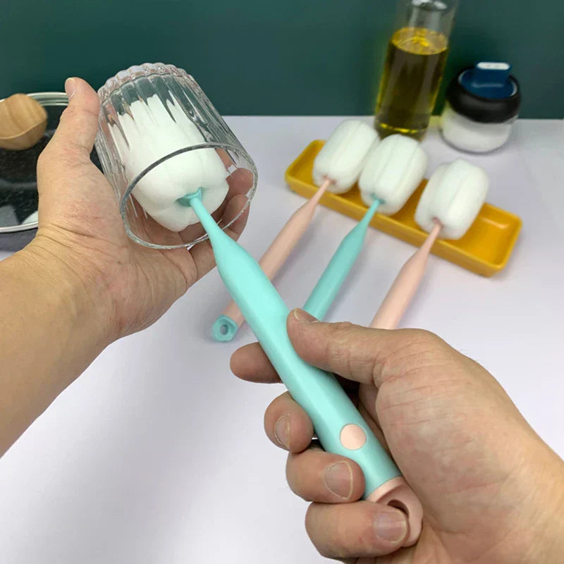 Sponge Bottle Cleaning Brush - Two hands holding a clear glass and a mint handled sponge brush cleaning inside the glass, with three other brushes resting on a yellow tray in the background