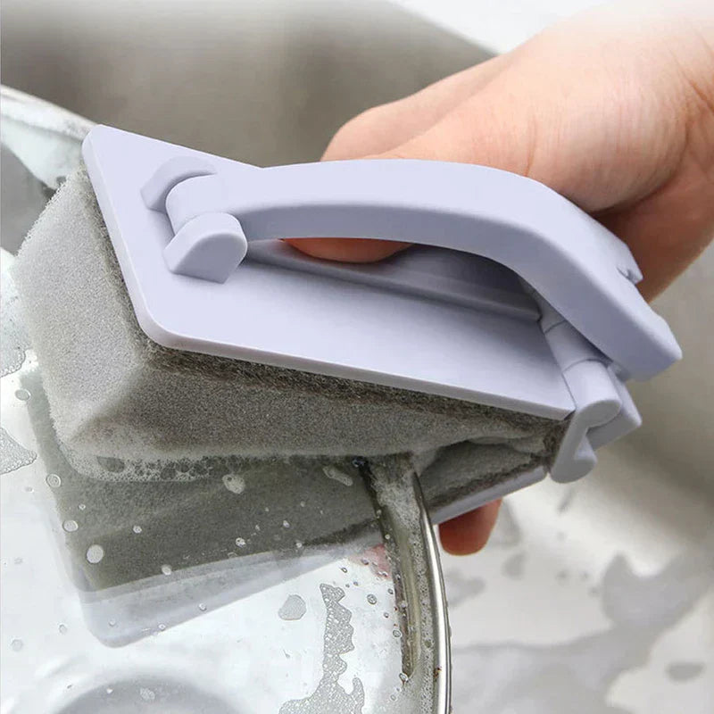 Cepillo de limpieza para ducha: mano sosteniendo el cepillo fregando un plato en un fregadero de acero inoxidable, con espuma en la esponja de limpieza