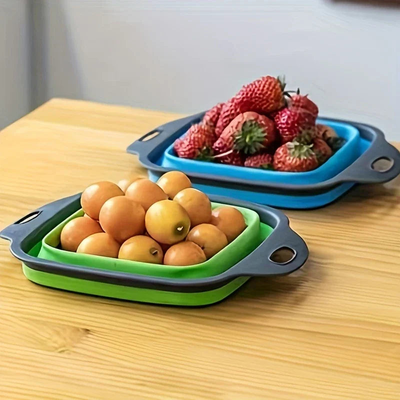 Square Plastic Colander Fruit Strainer Basket - Two collapsible colanders (green with loquats, blue with strawberries) resting on a light wooden table.