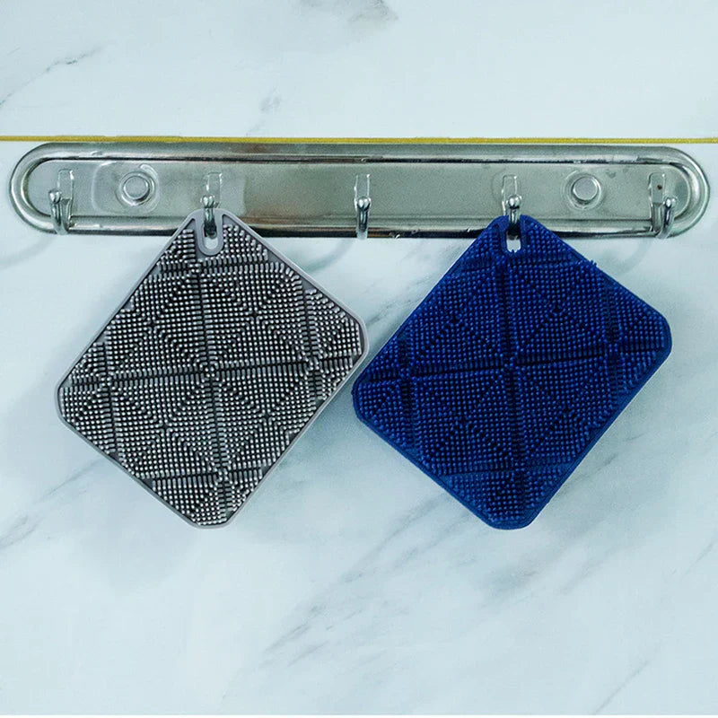 cepillo de ducha para el cuerpo - Dos almohadillas de cerdas cuadradas, una gris y una azul, cuelgan de un soporte de ganchos metálico