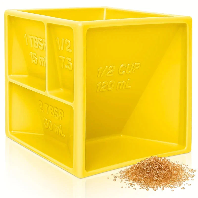 4 messbecher - Gelber Kunststoff-Messwürfel mit mehreren Fächern und Messmarkierungen, neben einem kleinen Haufen braunem körnigem Material auf einer weißen reflektierenden Oberfläche