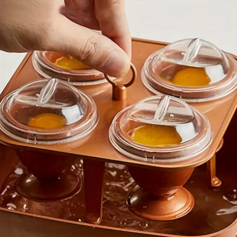 Stainless Steel Egg Ring Mold - A hand lifts the ring handle of a copper-toned 4-cup egg poacher tray holding raw yolks in covered cups over water.