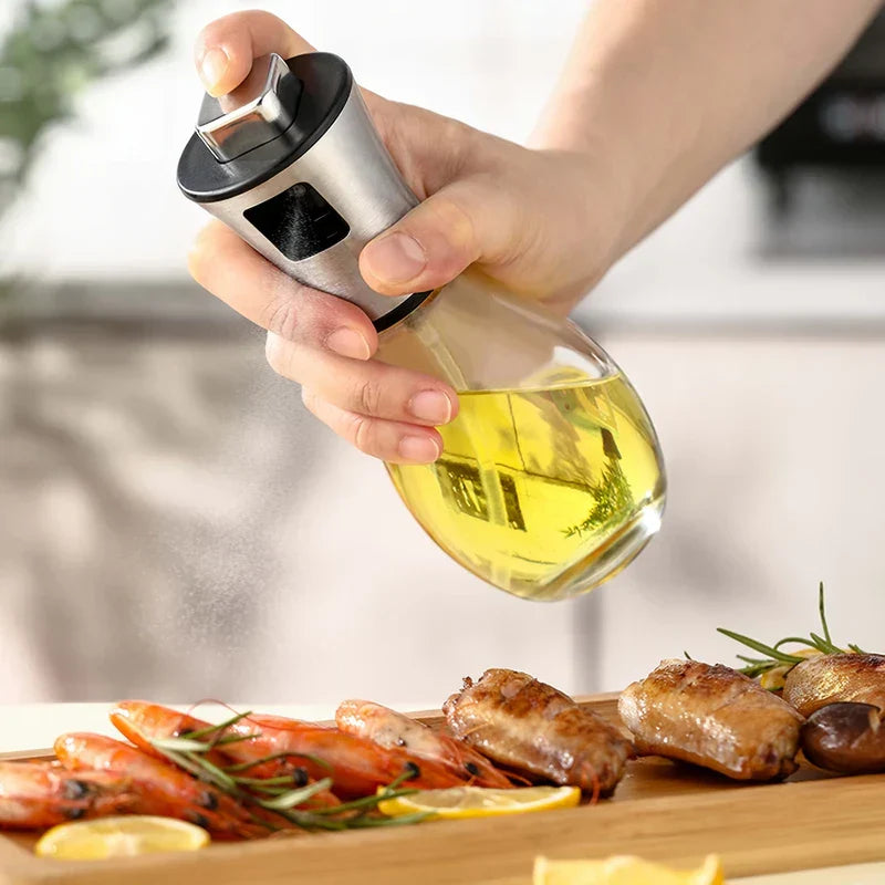 Oil Sprayer Mister - Hand pressing the spray trigger to dispense a fine mist over cooked shrimp and chicken on a wooden serving board