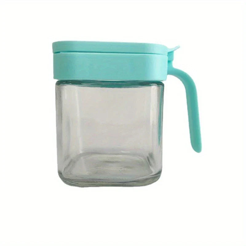Glass Spice Jar - Empty square glass jar with closed light blue lid and curved side handle, on plain white background.
