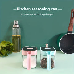 Glass Spice Jar - Pink and mint kitchen seasoning cans on a counter with an oil bottle, lettuce, and pan behind them