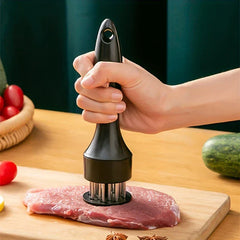 Stainless Steel Meat Tenderizer - Hand pressing pronged kitchen tool into raw meat on wood cutting board