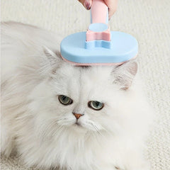 Pet Grooming Comb - Hand holding a pink and blue pet brush resting on a fluffy white cat’s head