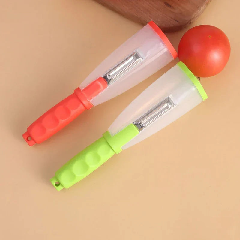 Storage Grater Box Container - Two storage peelers, one red and one green, sit on a tan surface beside a tomato