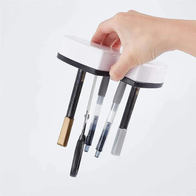 Storage Bin - A hand holds a white and black magnetic holder that suspends scissors and pens.
