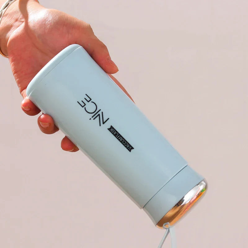 A hand holding a light blue plastic tumbler cup upside down, showing the cup's logo and silver cap