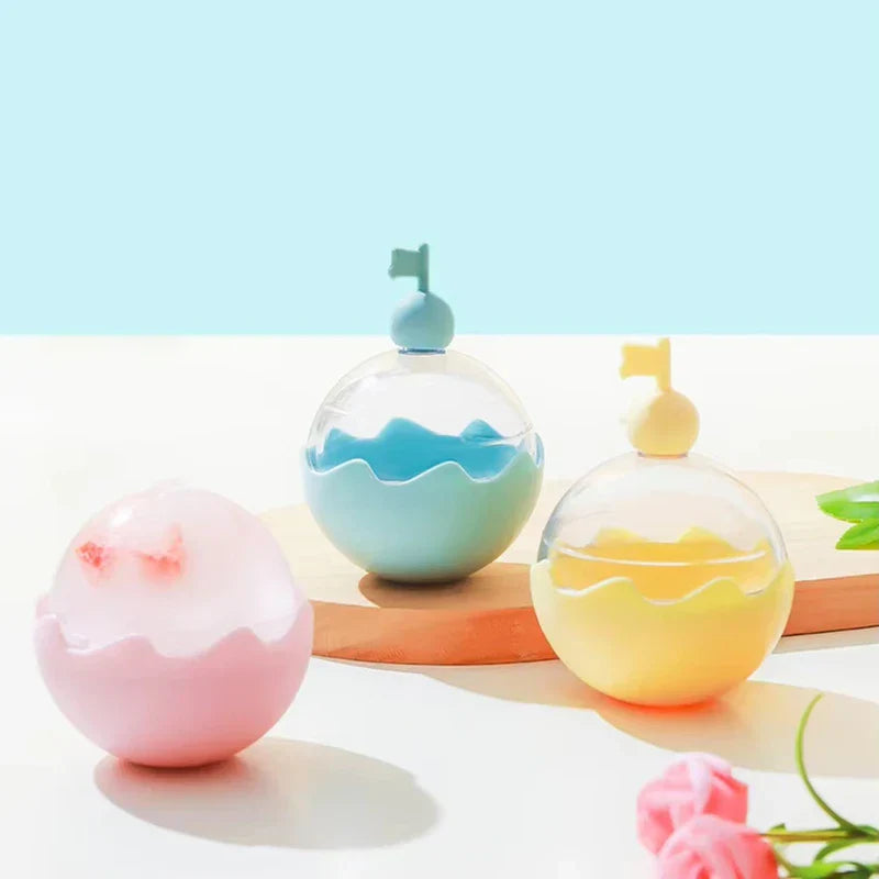 Ice Ball Mold - Three pastel colored spherical molds in pink, light blue, and pale yellow displayed on a light wood surface