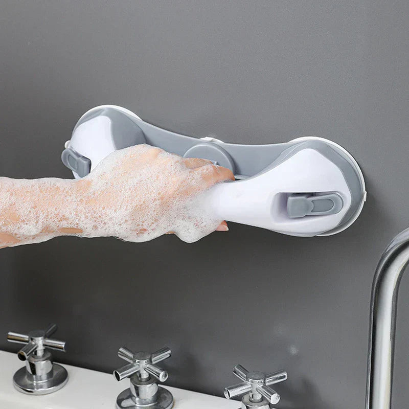 haltegriff mit saugnapf - Eine seifige Hand greift einen weißen und grauen Saugnapf-Haltegriff, der an einer grauen Wand über einer Badewannenarmatur montiert ist