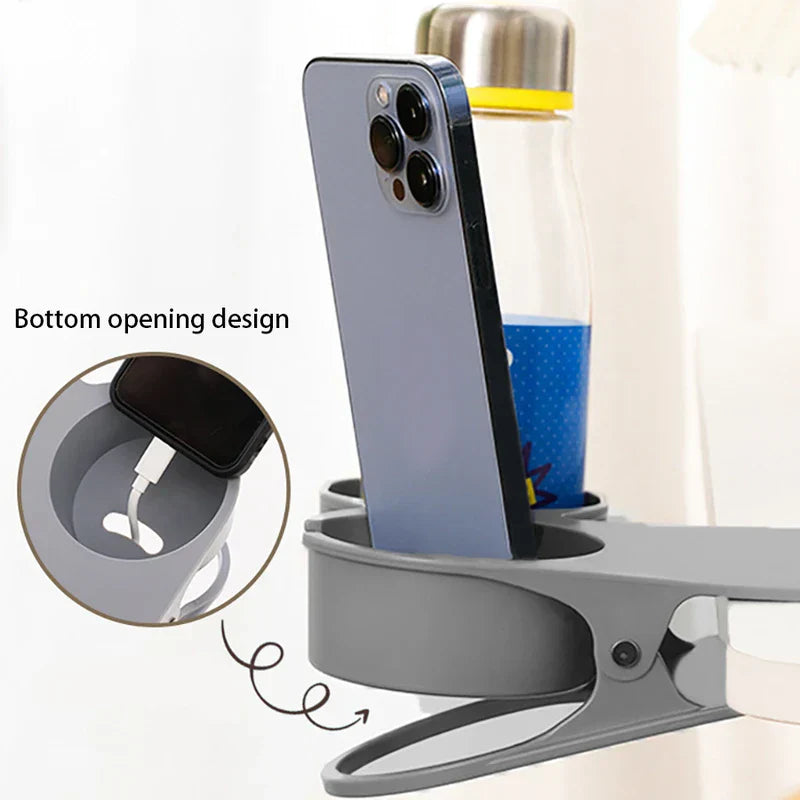 Soporte con pinza para bebidas de mesa - Portabebidas gris con clip que demuestra su diseño de apertura inferior, sosteniendo un teléfono inteligente en posición vertical con acceso al cable de carga y una botella de agua, con un recuadro ampliado de la ranura para pasar el cable