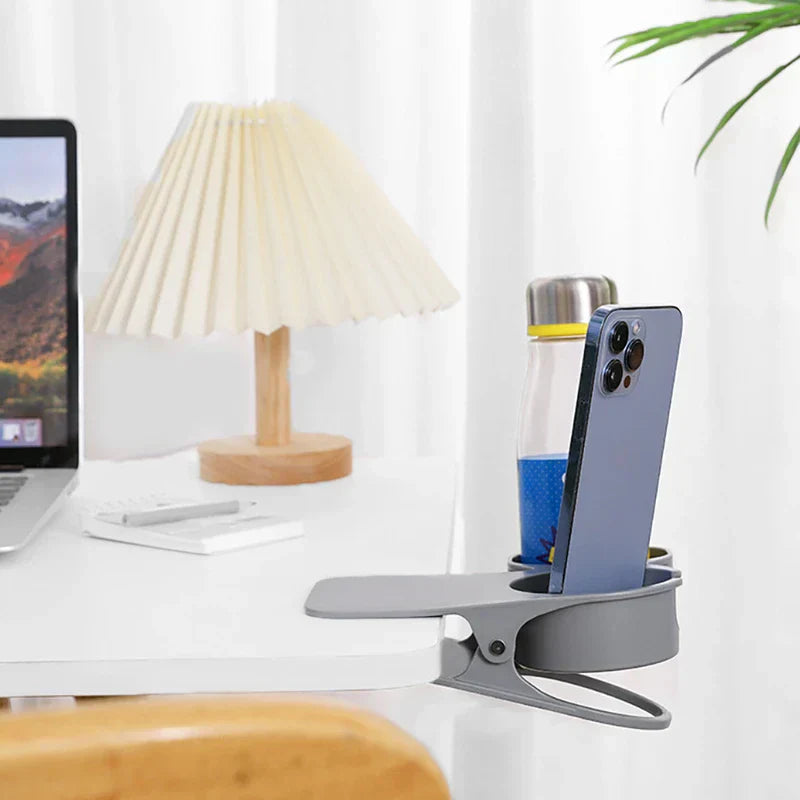 Table Side Drink Clamp Holder - Gray clip-on cup holder attached to a desk edge, holding a phone and a bottle