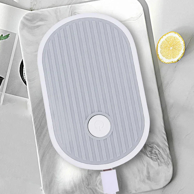Tubo de drenaje para bandeja de té: vista superior del dispositivo ovalado que muestra su botón de encendido y un cable USB conectado