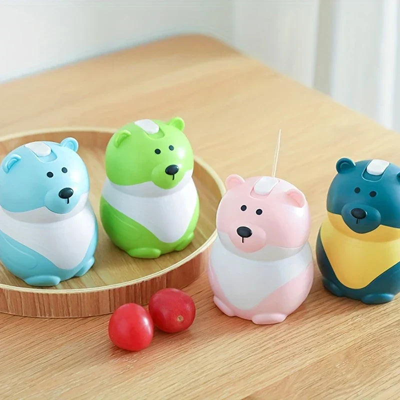 Sujetapalillos con forma de osito de peluche: cuatro sujetapalillos multicolores con forma de oso dispuestos sobre una mesa de madera y una bandeja redonda de madera, con dos pequeñas cerezas rojas colocadas frente a la bandeja