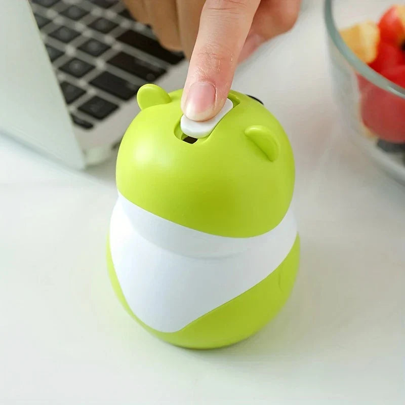 Sujetapalillos con forma de osito de peluche: primer plano de un dedo presionando el botón blanco superior de un recipiente verde lima con forma de oso de dibujos animados