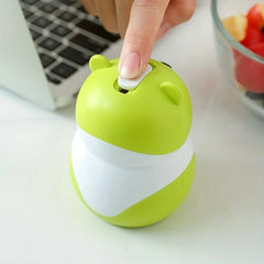 Sujetapalillos con forma de osito de peluche: primer plano de un dedo presionando el botón blanco superior de un recipiente verde lima con forma de oso de dibujos animados