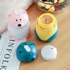 Sujetapalillos con forma de osito de peluche: dos sujetapalillos con forma de animalitos sobre una mesa de madera, uno abierto mostrando los palillos, con las tapas desprendidas a su lado