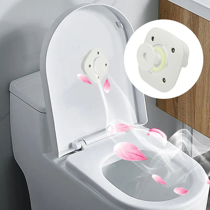 Sanitizer Light – Weißes Toilettengerät, montiert im Inneren eines geöffneten, angehobenen Toilettendeckels, mit rosa Blütenmotiven und luftstromartigen visuellen Effekten, vergrößerte Geräteansicht eingeblendet