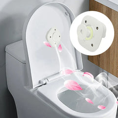 Sanitizer Light – Weißes Toilettengerät, montiert im Inneren eines geöffneten, angehobenen Toilettendeckels, mit rosa Blütenmotiven und luftstromartigen visuellen Effekten, vergrößerte Geräteansicht eingeblendet