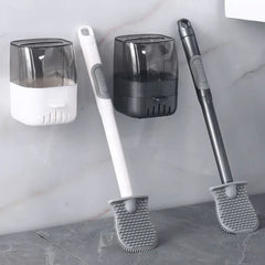 Two toilet brush sets with wall-mounted holders, one white and one dark gray, rest against a tiled wall.