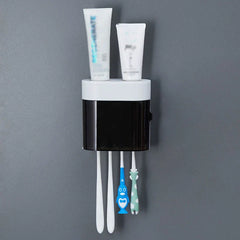 Wall mounted bathroom holder with toothbrushes hanging below and toothpaste tubes on top, featuring a toothpaste dispenser squeezer.