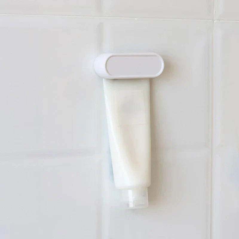 Toothpaste Tube Squeezer - White roller clip attached to a white squeeze tube mounted on a white tiled wall