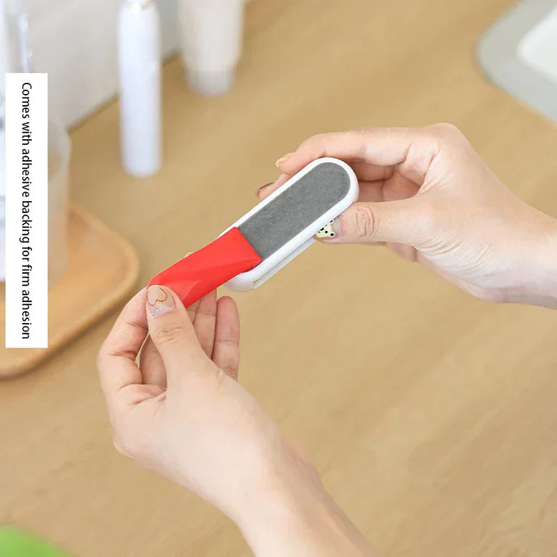 Toothpaste Tube Squeezer - Two hands peeling red adhesive backing off the white wall clip