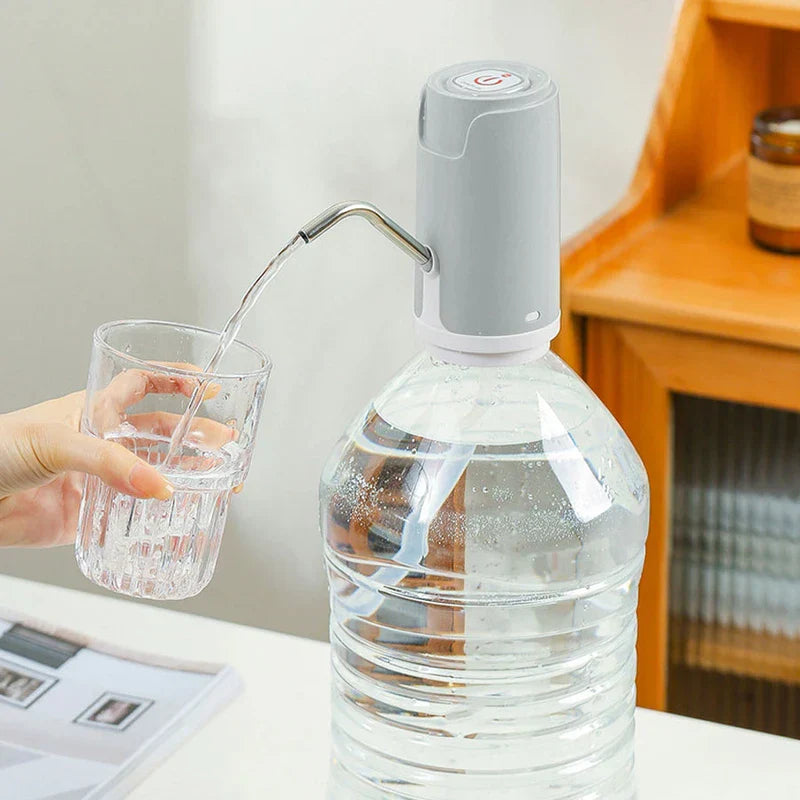 Gray water bottle pump dispenser attached to a clear water jug, pouring water into a held glass.