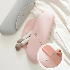 Makeup Brush Holder - Gray and pink silicone cases laid flat, with partial view of two makeup brushes and close-up of snap fastener detail