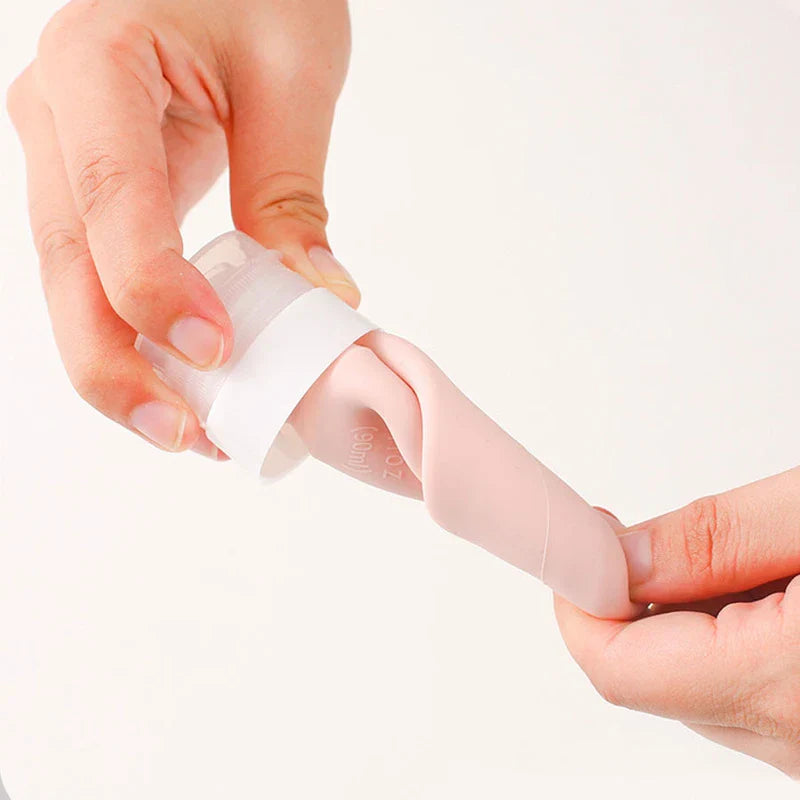 Travel Toiletry Bottles Set - Two hands handling an inverted, squeezed pink travel bottle, showing its flexible body and cap.