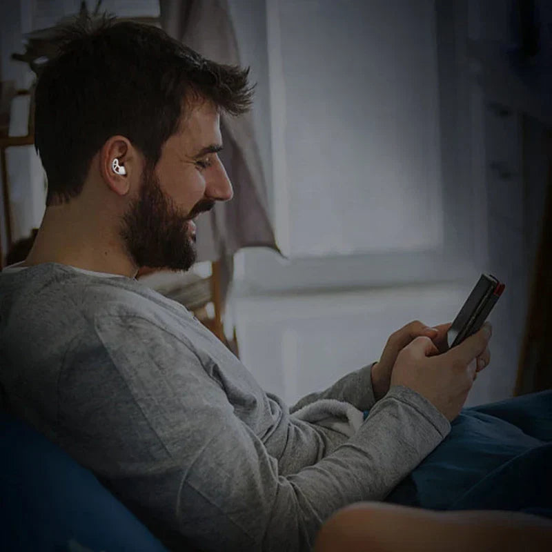 Noise Cancelling Ear Plugs - Person wearing a single ear plug while using a handheld device in bed