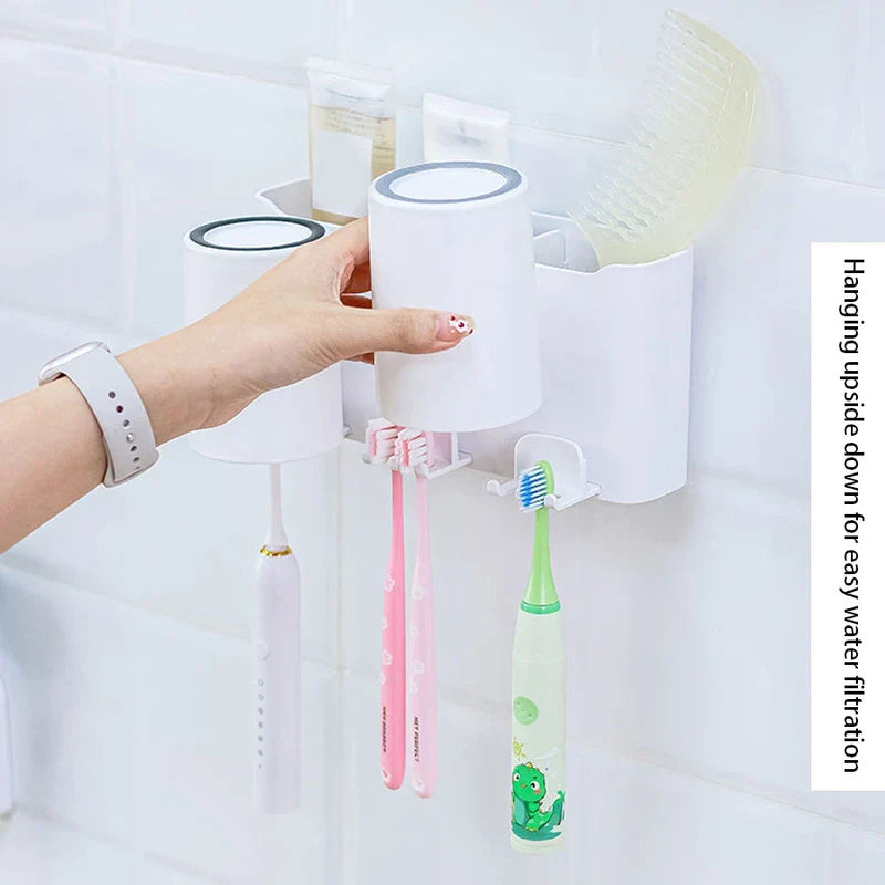 Toothbrush Holder - A hand holds an upside-down white cup above hanging toothbrushes mounted on a wall organizer.