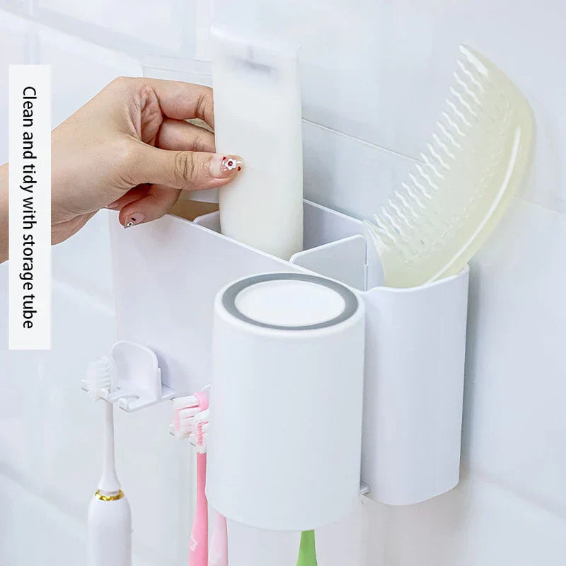 Toothbrush Holder - A hand places a white tube into the storage compartment of a wall organizer with hanging toothbrushes.