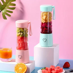 Portable Juicer - Two portable blenders filled with mixed cut fruit, displayed with a glass of orange juice, an orange slice, cut watermelon, and a strawberry