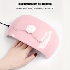 Nail Dryer - Pink nail lamp with bow design, shown with a hand inserted into the curing opening, against white.