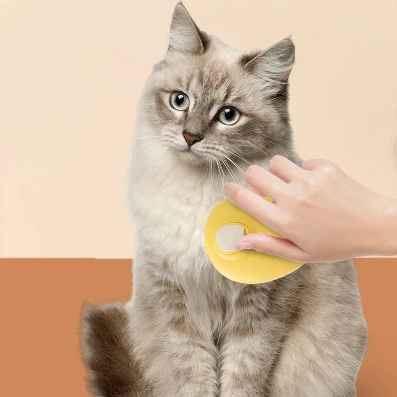 Uv Light Pet Grooming Comb - Hand holding a yellow grooming brush against a seated light gray longhair cat