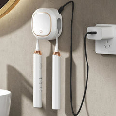 Uv Toothbrush Sanitizer Holder - White unit mounted on bathroom wall connected to a wall power adapter, holding two electric toothbrushes