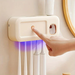 Uv Toothbrush Sterilizer - Finger pressing power button on wall-mounted device, purple UV light illuminating hanging toothbrushes